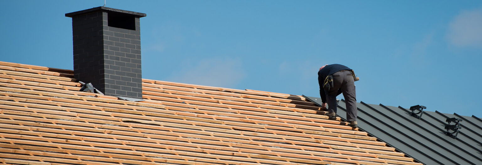 Chimney cap with a person besides it on a roof